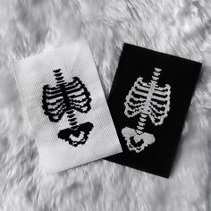 two black and white knitted patches with skeleton designs on them sitting on a furry surface