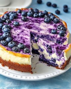 a blueberry cheesecake with one slice cut out and ready to be eaten on a plate