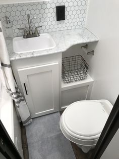 a white toilet sitting next to a sink in a bathroom