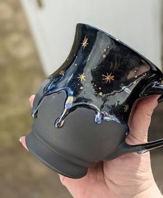 a hand holding a black coffee mug with stars on it