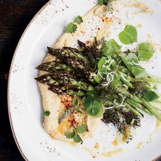 a white plate topped with green vegetables on top of a wooden table