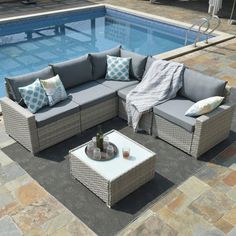 an outdoor sectional set next to a swimming pool with pillows and throw pillows on it