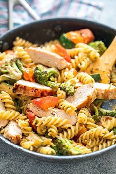 a skillet filled with pasta, chicken and veggies