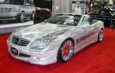 a silver car is on display in a showroom with other cars and people looking at it