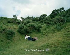 a man laying on top of a lush green hillside