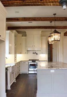 an empty kitchen with white cabinets and wood floors