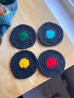 four crocheted coasters sitting on top of a wooden table next to a pair of shoes