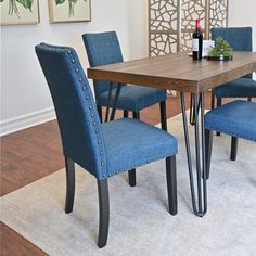 a dining room table with blue chairs and a wine bottle on the end shelf next to it