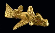 a gold brooch with a bird on it's back and wings spread out