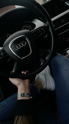 a person holding the steering wheel of an audi car