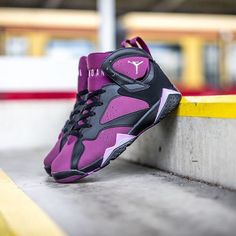 a pair of purple and black sneakers sitting on top of a cement bench