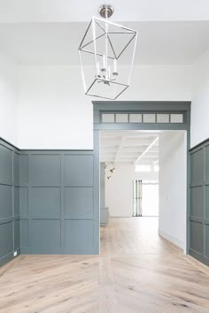 an empty room with wood flooring and gray paneling on the walls is shown