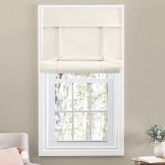 a window with a white roman blind in front of it and a chair next to it