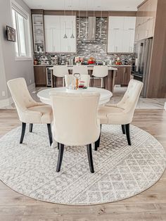 the dining room table is surrounded by white chairs