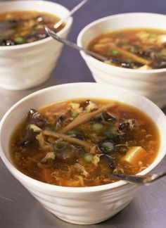 three white bowls filled with soup on top of a table