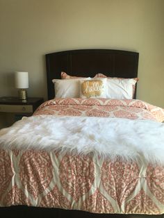 a bed with white fur on top of it and two nightstands in the background