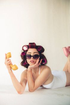 a woman laying on the floor with her hair in rollers and holding a banana