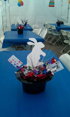 a blue table topped with a black basket filled with cards and flowers on top of it