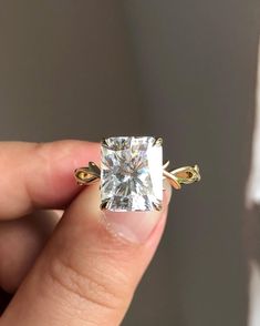 a person holding a ring with a diamond in it's middle and gold band around their fingers