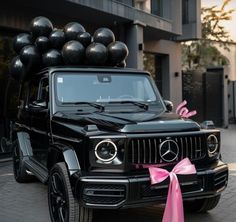 a black mercedes benz with balloons on top