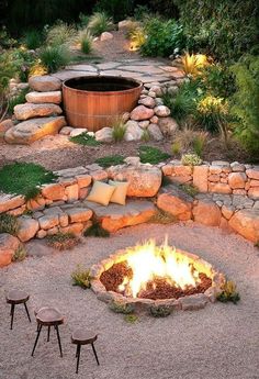 an outdoor fire pit surrounded by rocks and gravel