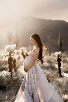 a pregnant woman is standing in the desert