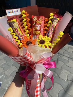 a person holding a bouquet of candy and candies