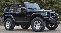 a black jeep is parked in front of some trees