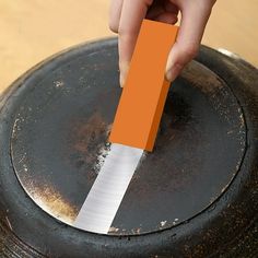 a person is holding an orange piece of paper in front of a rusted metal object