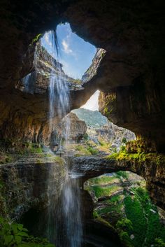 a waterfall is seen from the inside of a cave