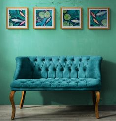 a blue couch sitting in front of three paintings