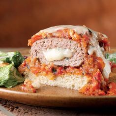 a meatloaf sandwich on a plate with lettuce and tomato salad next to it