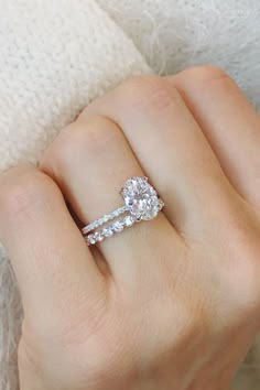 a woman's hand with a diamond ring on top of her finger and the other hand holding an engagement ring