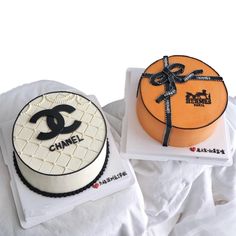 two cakes decorated to look like chanel and one with a bow on top are sitting on white napkins