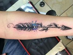 a woman's arm with a feather and arrow tattoo on the left side of her arm