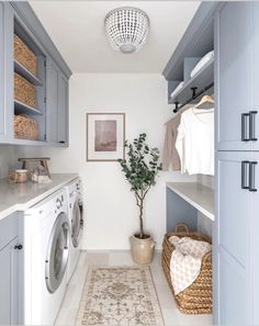 a washer and dryer in a laundry room with blue cabinets, white counter tops and drawers