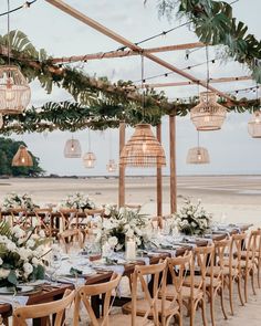 an outdoor dining area with wooden chairs and tables set up for a wedding reception on the beach