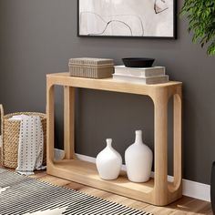 a wooden table with two vases on it in front of a gray wall and black and white striped rug