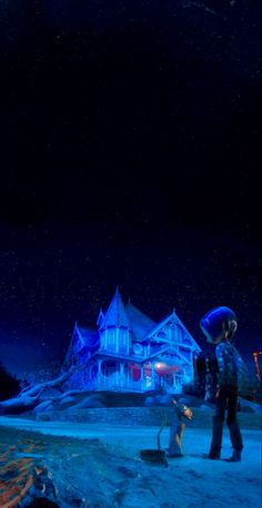 two people standing in front of a large house with snow on the ground at night