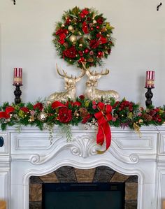 a mantel decorated for christmas with red and gold decorations, deer heads and wreaths