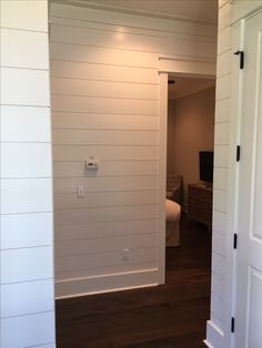 an open door leading to a bedroom with white walls and wood floors in the background