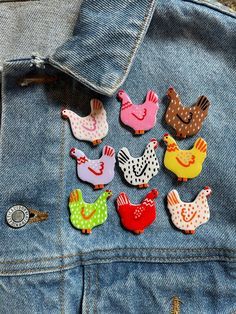 a denim jacket with several different colored chickens on the back and one in the pocket