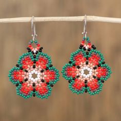 two pairs of beaded earrings hanging from a wooden stick