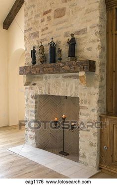 a stone fireplace with candles and figurines on the mantel in an empty room