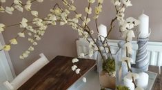 white flowers are in vases on a table with candles and other items around it