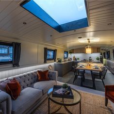 a living room filled with furniture and a skylight above the couches in front of a kitchen