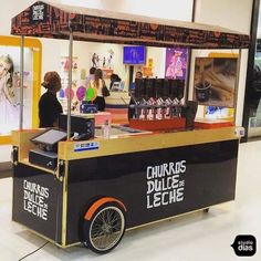 an ice cream cart in a store with people standing around it and looking at items on the counter