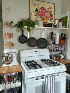 a white stove top oven sitting inside of a kitchen next to a wall mounted pot rack