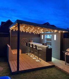 an outdoor bar is lit up at night with lights on the roof and barstools