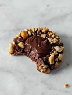 a cookie with chocolate frosting and walnuts on it sitting on a marble surface